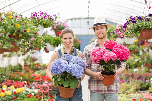 Lächelnde Gärtner mit Blumentöpfen — Stockfoto