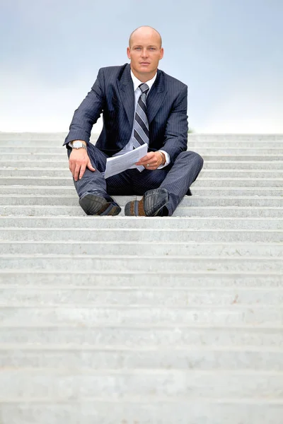 Businessman holding document on steps — Stock Photo, Image