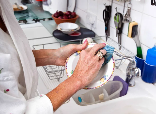 Senior woman cleaning plate — Stock Photo, Image