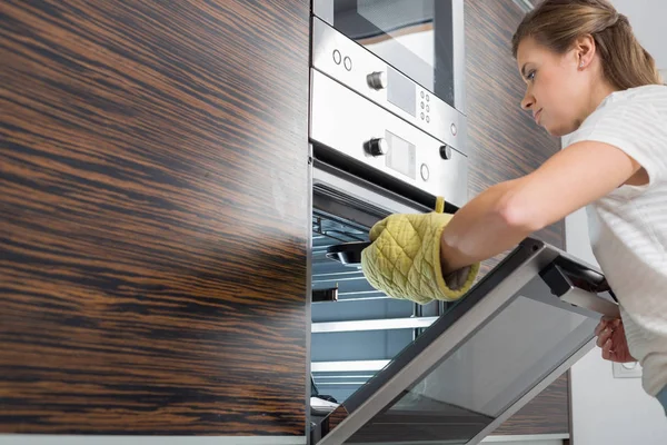 Woman placing dish in oven — Stock Photo, Image