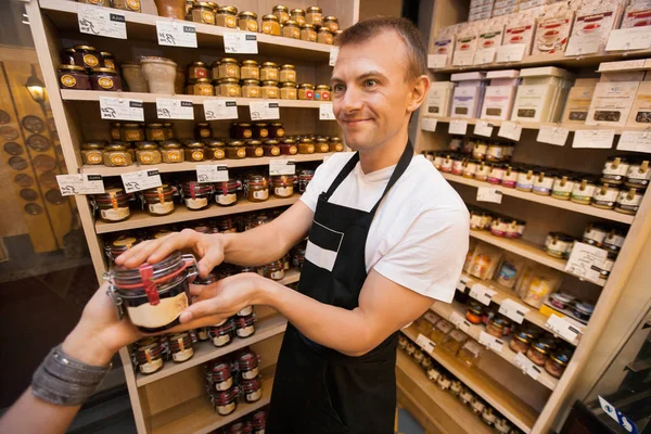 Salesman giving jar of jam to customer — Stock Photo, Image