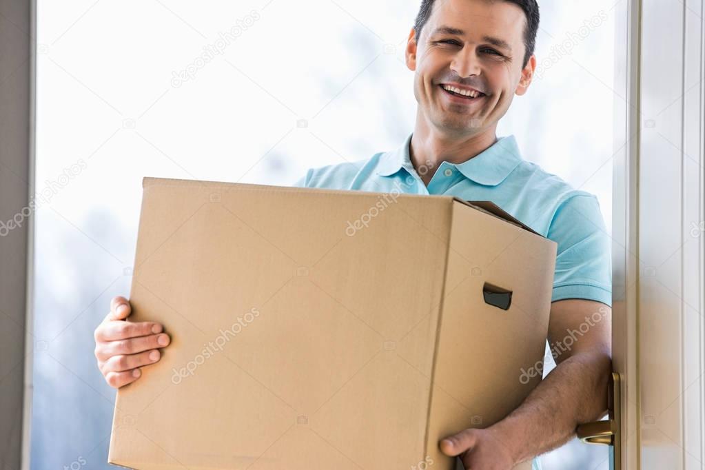Happy man carrying cardboard box 