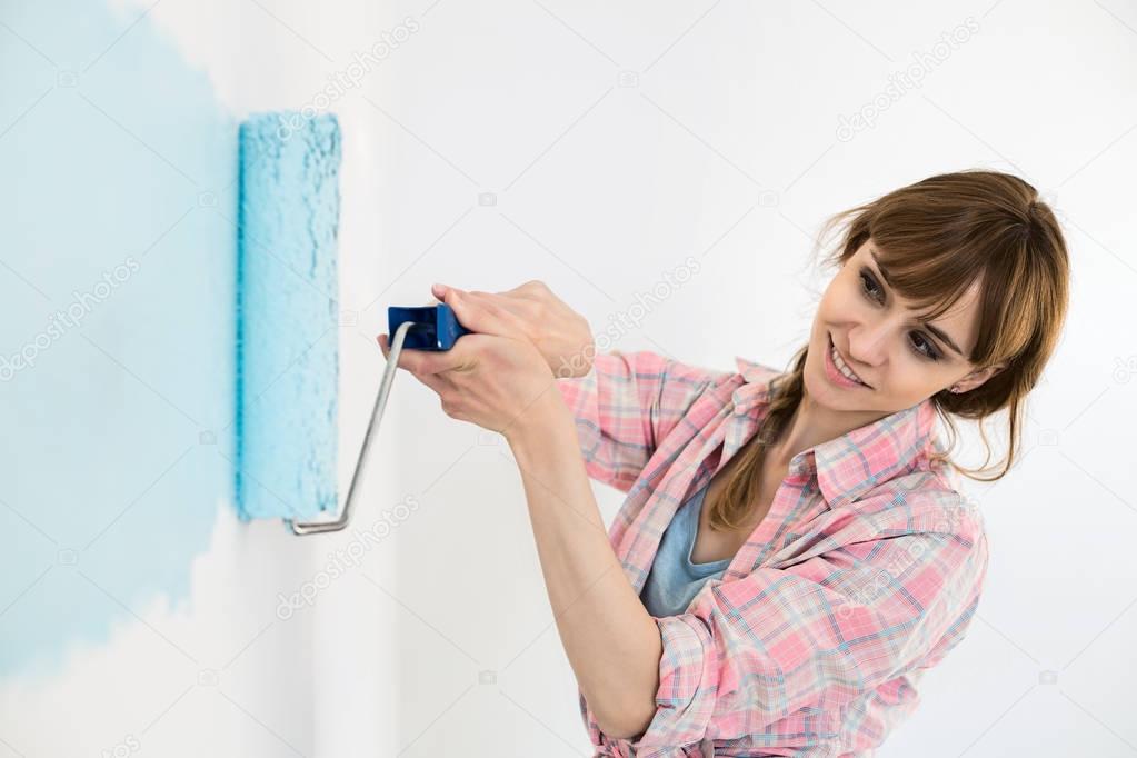 Beautiful woman painting wall
