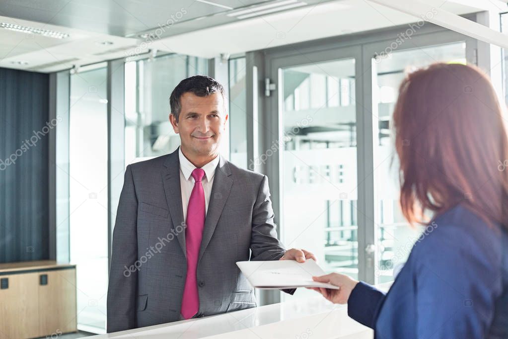 Businessman receiving document from receptionist