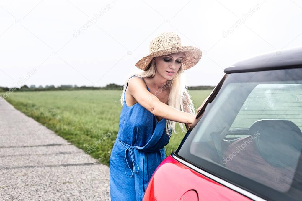 Woman pushing broken down car 