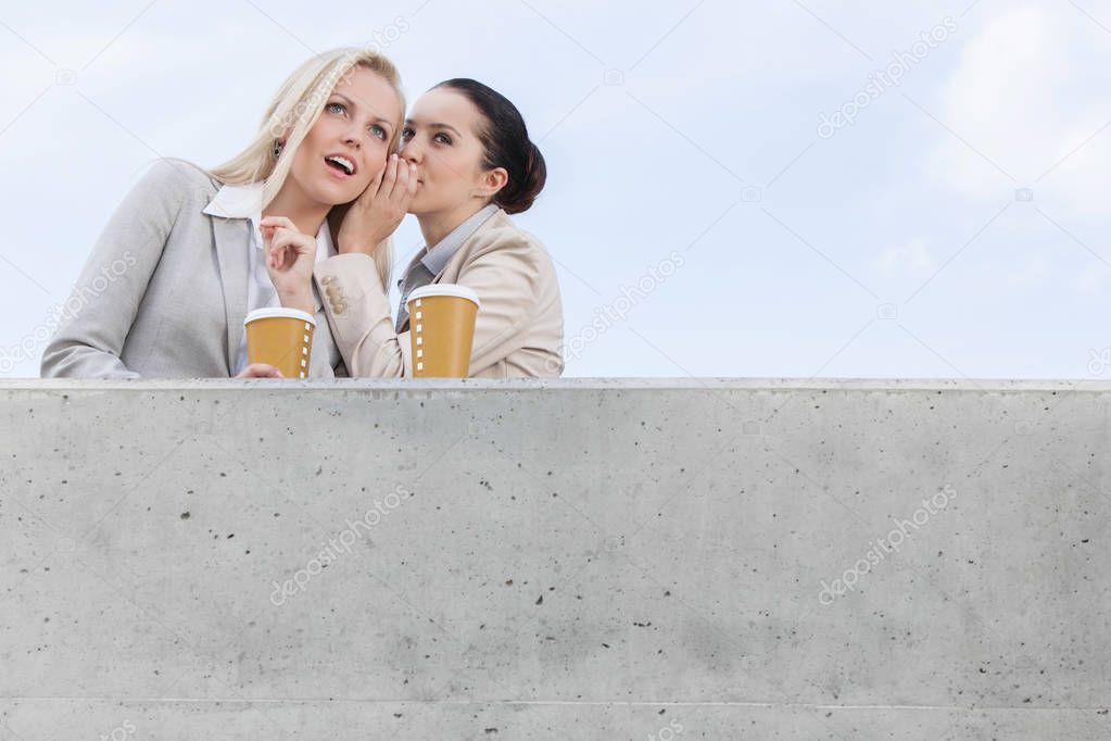 Businesswoman whispering with coworker