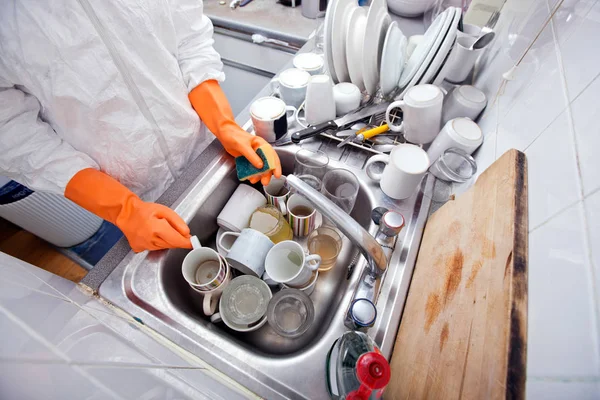 Mains féminines dans des gants laver les ustensiles de cuisine — Photo