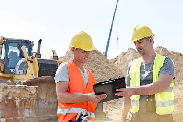 Engineers reading clipboard at construction site — Stock Photo, Image