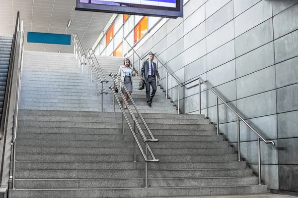 Businessman and businesswoman walk down stairs — Stock Photo, Image
