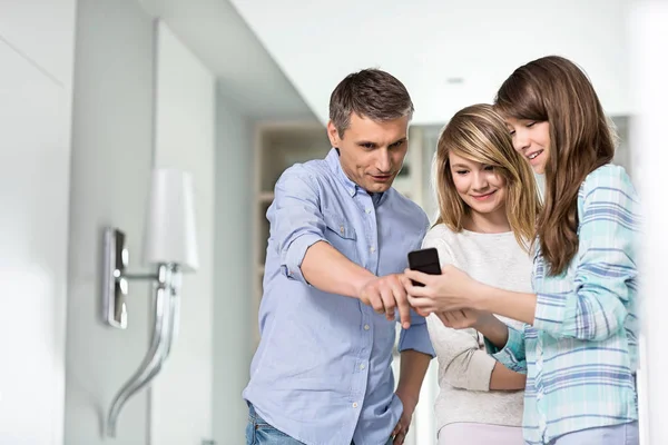 Чоловік з дочками за допомогою смартфона — стокове фото