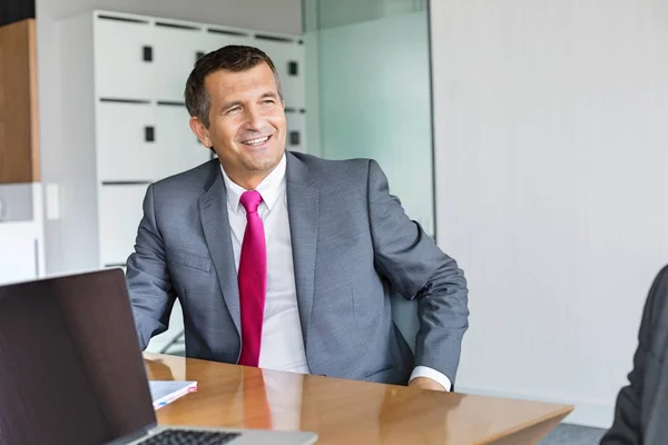 Businessman sitting at desk in office — Stock Photo, Image
