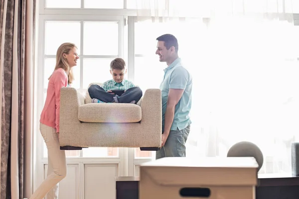 Happy parents carrying son on armchair — Stock Photo, Image