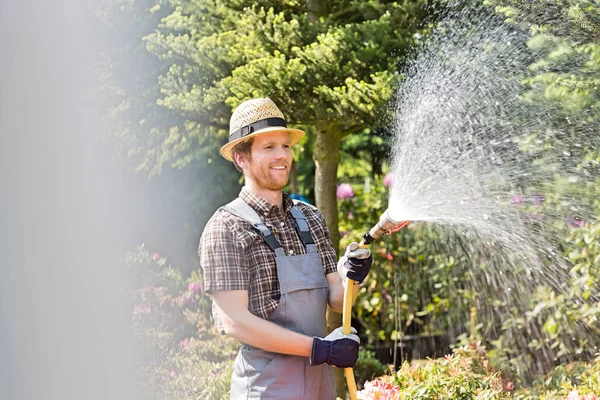 Glücklicher Mann, der Pflanzen gießt — Stockfoto