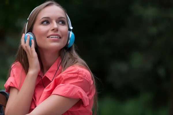 Zenehallgatás fejhallgató csatlakozó parkban nő — Stock Fotó