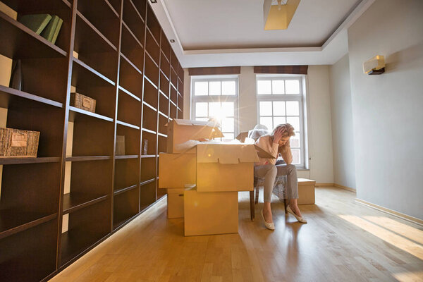 Стрессовая женщина сидит за картонными коробками
