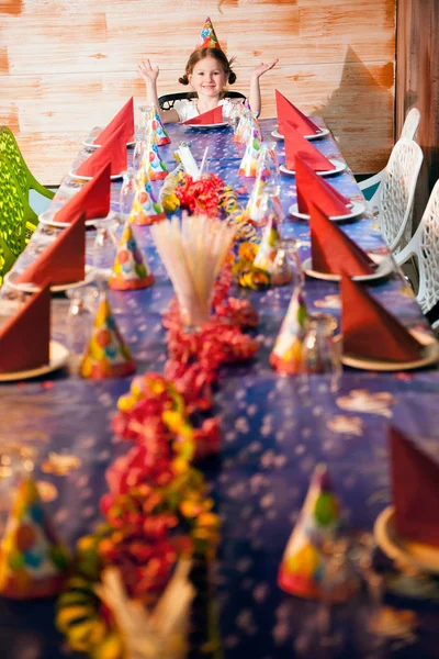 Menina na mesa de aniversário vazia — Fotografia de Stock