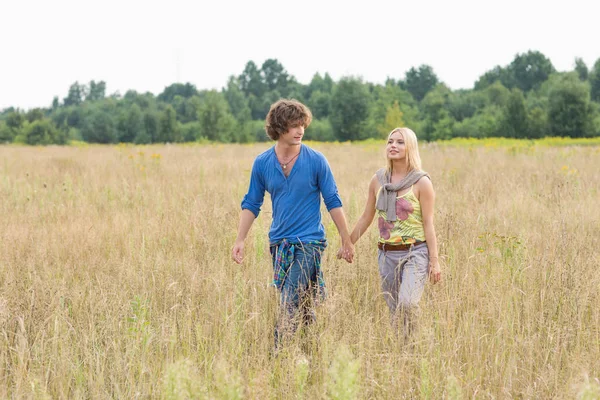 Jovem casal caminhando através do campo — Fotografia de Stock