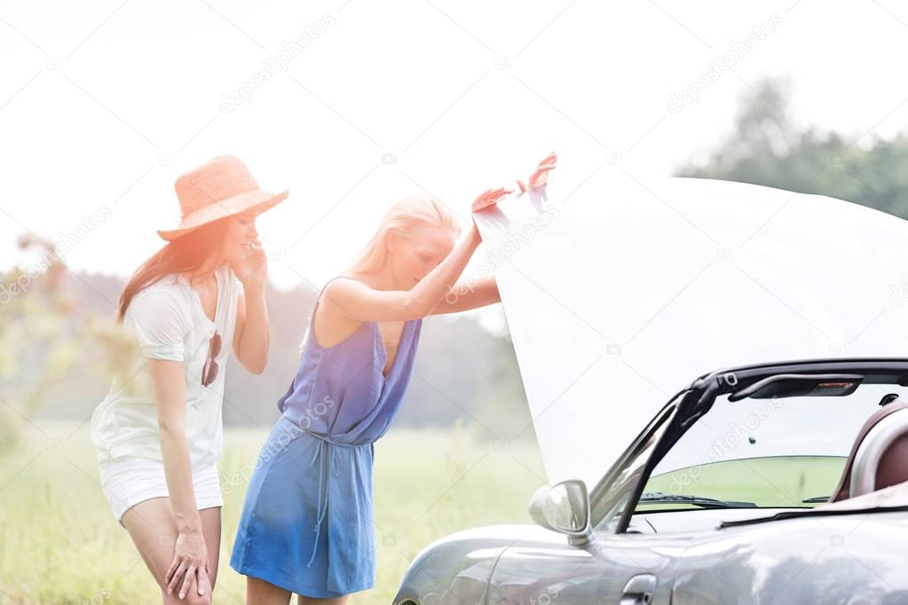 Friends examining broken down car 