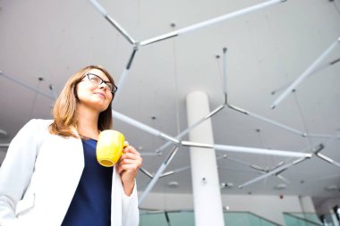 Ofiste dururken kahve bardağı tutan iş kadınının düşük açılı görünümü
