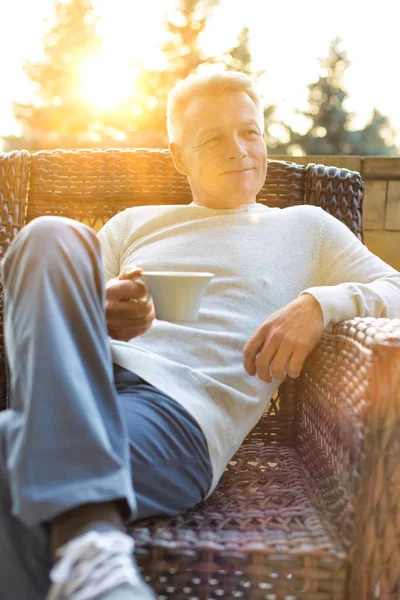 Senior Man Sitting While Drinking Coffee Home Yellow Lens Flare — Stock Photo, Image