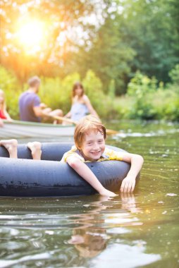 Aile karşı gölde şişme halka ile yüzen gülümseyen çocuk Portresi