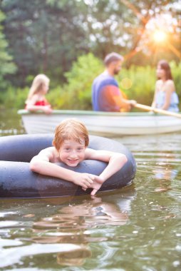 Aile karşı gölde şişme halka ile yüzen gülümseyen çocuk Portresi