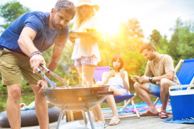 İskelede göl kenarında barbekü yapan mutlu çiftler.