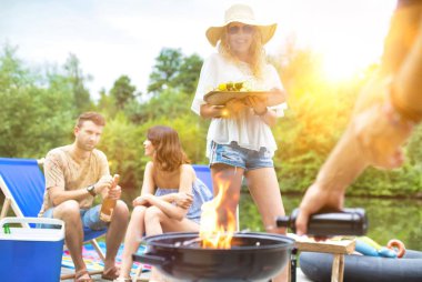 İskelede göl kenarında barbekü yapan mutlu çiftler.