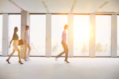 Ofiste çalışan işadamları, arka planda sarı lens ışığıyla yürüyorlar.