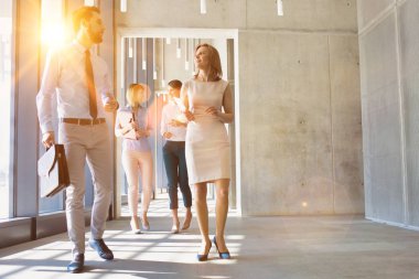 İş adamları ofiste yürürken planlarını tartışıyor. 