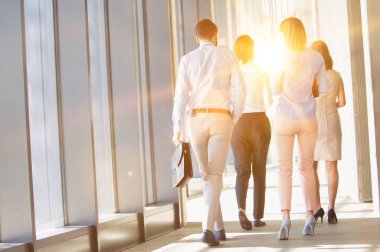 Ofiste yürüyen iş adamları sarı mercekli işaret fişeğiyle konuşuyor. 