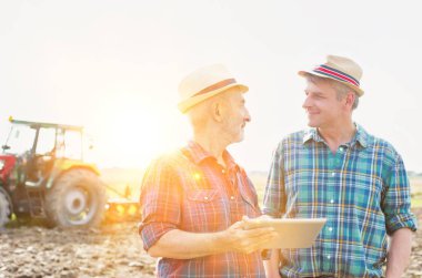 Dijital tablet Çiftliği'nde güneşli günde kullanırken konuşurken çiftçiler