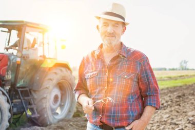 Kendine güvenen üst düzey Çiftçi traktör çiftliğinde karşı daimi portresi