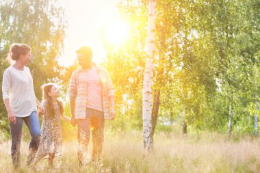 Çiftlikte gökyüzüne karşı çimenli alanda yürüyüş aile