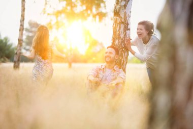 husband looking at mother playing with daughter on field at farmland