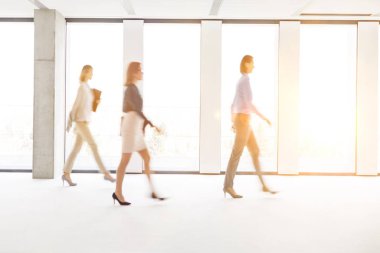 Ofiste çalışan işadamları, arka planda sarı lens ışığıyla yürüyorlar.