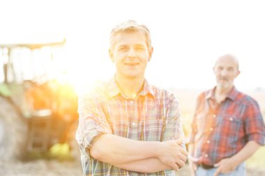 Yaşlı çiftçiye karşı ayakta duran kendinden emin yetişkin çiftçi. Arka planda sarı mercek fişeği var. 