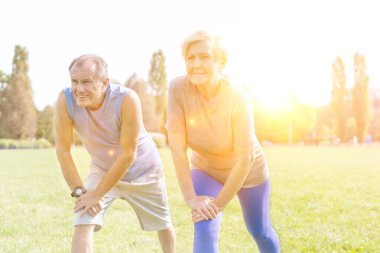 Fit senior couple doing stretching exercise in park
