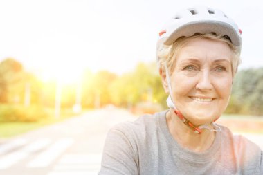 Confident senior woman smiling in helmet in park