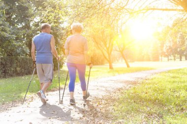 Senior couple with hiking poles walking outdoors