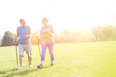 Senior couple with hiking poles walking outdoors