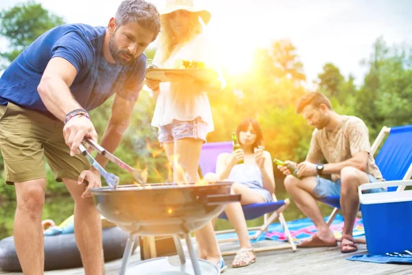 İskelede göl kenarında barbekü yapan mutlu çiftler.