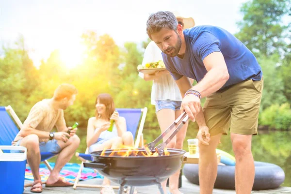 İskelede göl kenarında barbekü yapan mutlu çiftler.