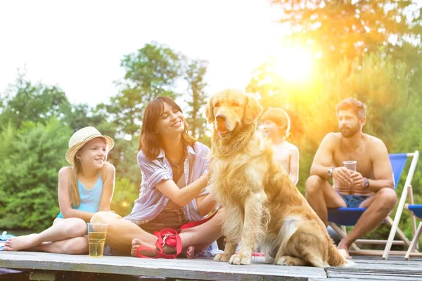 Happy family having picnic in pier at lake with their golden retriever dog
