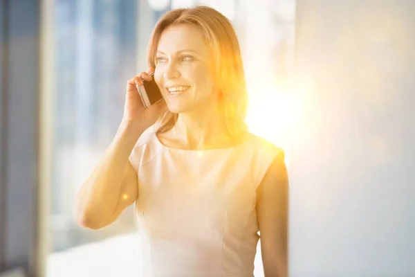 Podnikatelka Usmívá Zatímco Mluví Smartphone Kanceláři Žlutou Čočkou Světélkování Pozadí — Stock fotografie