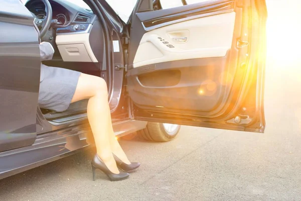 黄色のレンズフレアを背景に車を降りるビジネスマン女性 — ストック写真