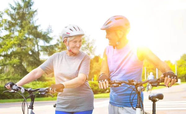 senior couple walking with bicycles in park