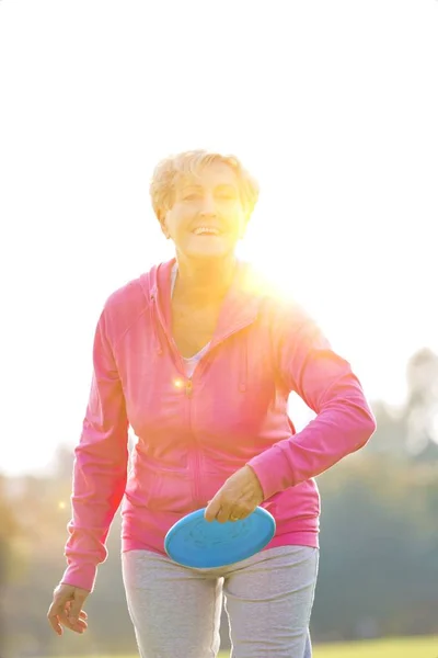 Sorridente Sana Donna Anziana Lancio Del Disco Nel Parco — Foto Stock