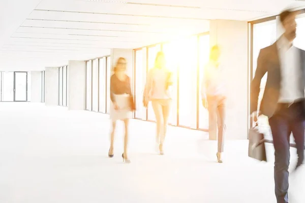 黄色のレンズフレアを背景にオフィスホールを歩くビジネスマン — ストック写真