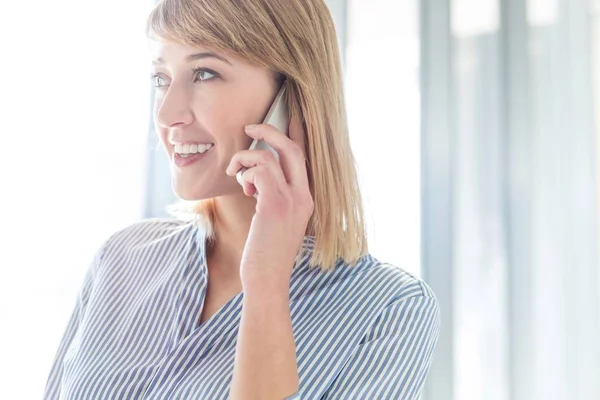 Geschäftsfrau Lächelt Während Sie Büro Mit Dem Smartphone Spricht — Stockfoto